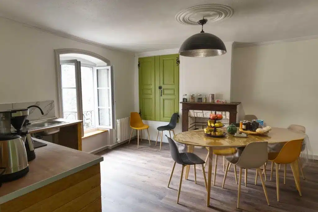 Grande pièce à vivre lumineuse du gîte Le Repose Pieds avec cuisine ouverte, table à manger design et volets bois authentiques